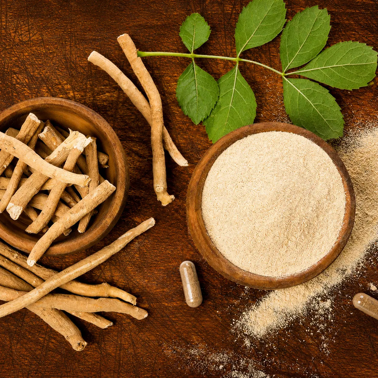 Ashwagandha roots and herbal powder in wooden bowls with fresh leaves, representing natural Ayurvedic wellness.