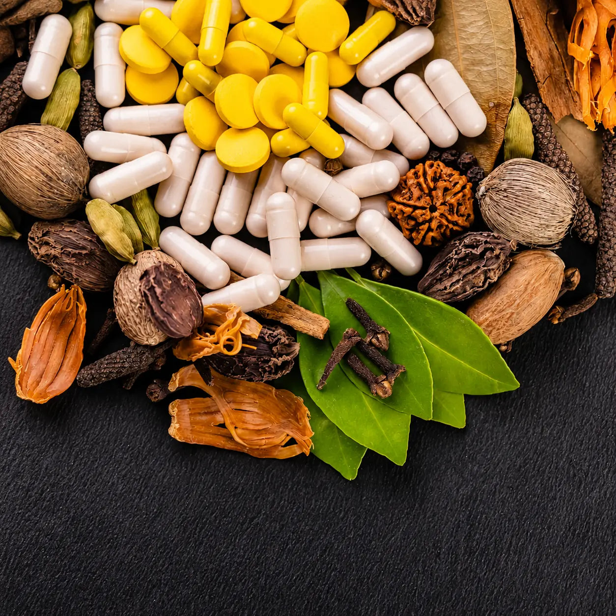 Ayurvedic herbs, spices, medicinal leaves, and herbal capsules arranged on a dark background, representing natural wellness and traditional herbal medicine