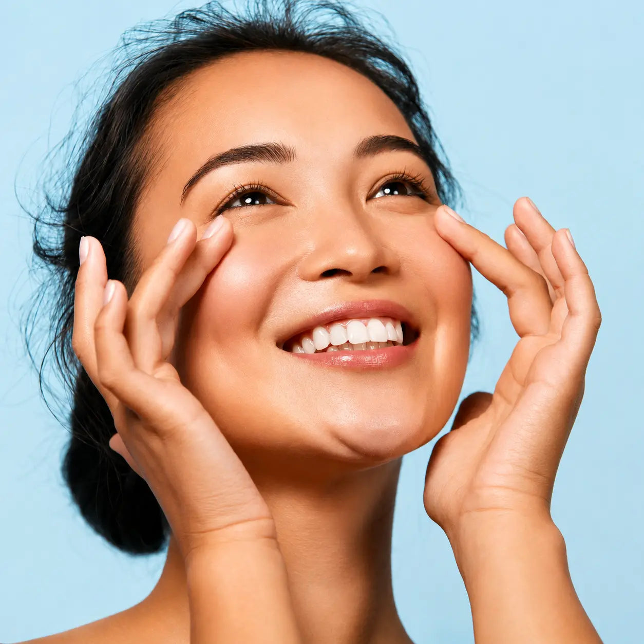 Smiling woman with healthy, glowing skin gently touching her face, representing natural skincare and Ayurvedic beauty.