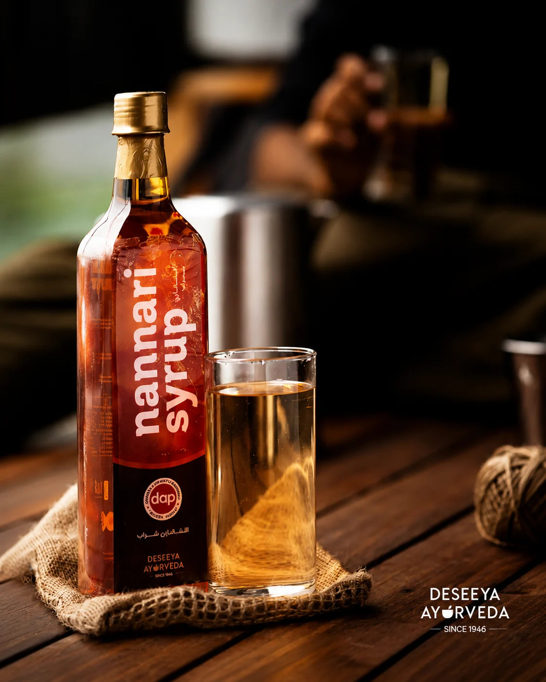 Bottle of Deseeya Ayurveda Nannari Syrup served with a refreshing glass of herbal drink on a wooden table.
